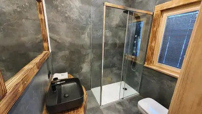 a bathroom with a shower with a toilet and a sink at Luksusowy domek z jaskinią SPA - Osada Jaworzyny in Tokarnia