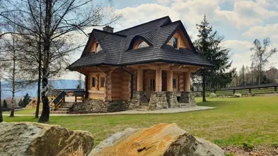 a small house with a black roof on a field at Luksusowy domek z jaskinią SPA - Osada Jaworzyny in Tokarnia
