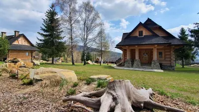 a house with a tree stump in front of it at Luksusowy domek z jaskinią SPA - Osada Jaworzyny in Tokarnia