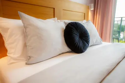 a black pillow sitting on a bed with pillows at Bochenka Apartments II in Kraków