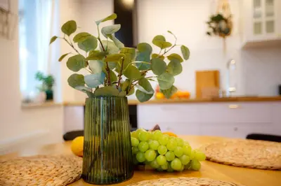 a vase with a plant and grapes on a table at Bochenka Apartments II in Kraków