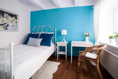 a bedroom with a blue wall and a bed and a chair at Urban Nest Apartments Szewska 21-19 in Kraków