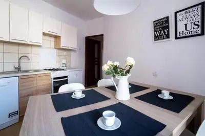 a kitchen with a table with chairs and a vase of flowers at Urban Nest Apartments Szewska 21-19 in Kraków