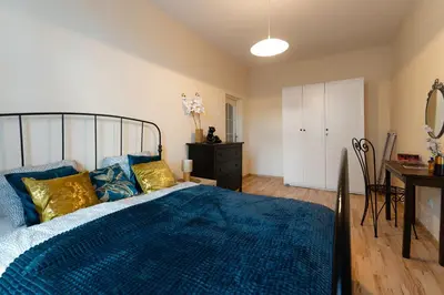 a bedroom with a bed with a blue comforter and a desk at Negroni Apartments Dajwor in Kraków