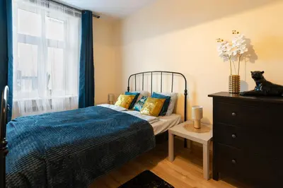a bedroom with a bed with blue sheets and a window at Negroni Apartments Dajwor in Kraków