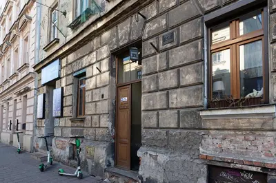 a stone building with a wooden door on a street at Negroni Apartments Dajwor in Kraków