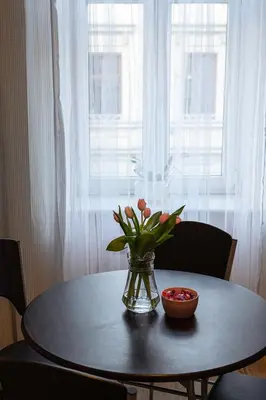 a vase of flowers on a table with a window at Negroni Apartments Dajwor in Kraków