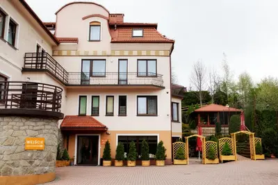 a large white house with a gate in front of it at Janda Resort & Conference in Mszana Dolna
