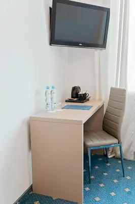 a desk with a chair and a tv on a wall at Janda Resort & Conference in Mszana Dolna