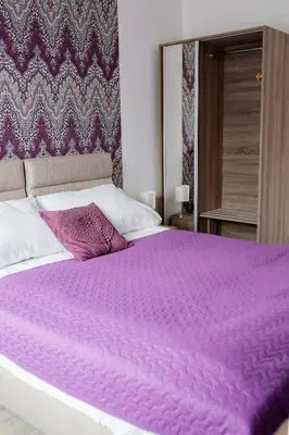 a bed with a purple blanket on top of it at Janda Resort & Conference in Mszana Dolna