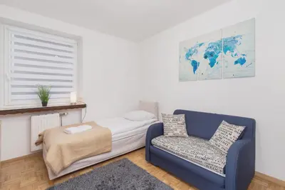 a bedroom with a bed and a couch and a chair at Retro Family Apartment Mały Płaszów by Noclegi Renters in Kraków