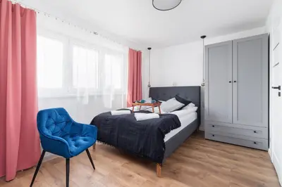 a bedroom with a bed and a blue chair at Apartments Kraków Czarnowiejska by Noclegi Renters in Kraków