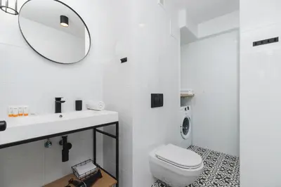 a white bathroom with a toilet and a mirror at Apartments Kraków Czarnowiejska by Noclegi Renters in Kraków