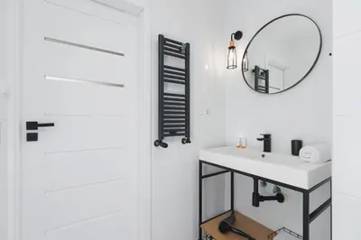 a white bathroom with a sink and a mirror at Apartments Kraków Czarnowiejska by Noclegi Renters in Kraków