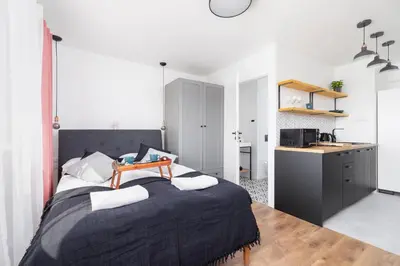 a bedroom with a large bed and a kitchen at Apartments Kraków Czarnowiejska by Noclegi Renters in Kraków