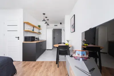 a room with a bed and a kitchen with a table at Apartments Kraków Czarnowiejska by Noclegi Renters in Kraków