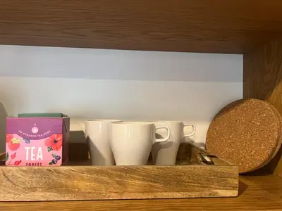 a shelf with three coffee cups and a box at By The River in Kraków