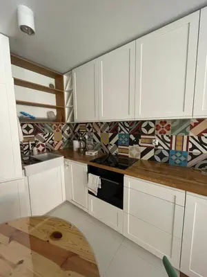 a kitchen with white cabinets and a wooden table at By The River in Kraków