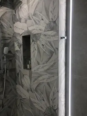 a bathroom with a shower with a floral wallpaper at Apartament Best Rest in Wadowice