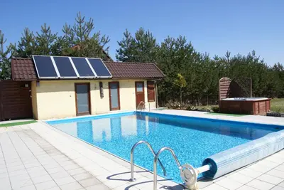 a swimming pool with a house with solar panels on it at Agro-Gala in Rabka