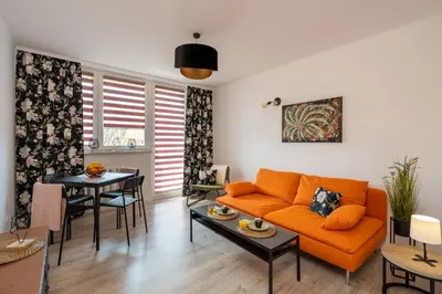 a living room with an orange couch and a table at Staymoovers - Ladne mieszkanie w poblizu Energylandii - Parking in Zator