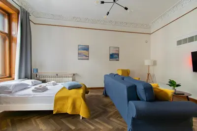 a bedroom with a bed and a blue couch at Magnificent Apartments Zyblikiewicza 11a, central location in Kraków