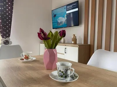 a table with two cups and a vase with purple flowers at Domek całoroczny Zagroda MłyńSKI in Sułkowice