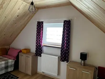 a attic room with a window with polka dot curtains at Domek całoroczny Zagroda MłyńSKI in Sułkowice