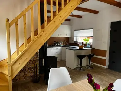 a kitchen and dining room with a wooden staircase at Domek całoroczny Zagroda MłyńSKI in Sułkowice