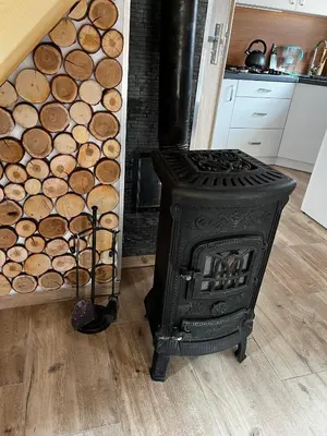 a stove in a kitchen next to a room with logs at Domek całoroczny Zagroda MłyńSKI in Sułkowice