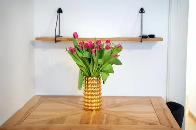 a vase with pink flowers sitting on a table at KrakowApart Zyblikiewicza in Kraków