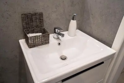 a white bathroom sink with a soap dispenser on it at KrakowApart Zyblikiewicza in Kraków
