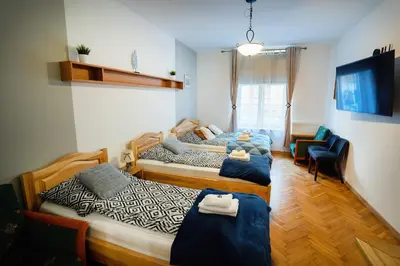 a bedroom with three beds and a chair and a couch at KrakowApart Zyblikiewicza in Kraków