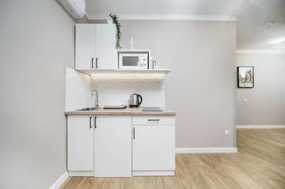 a kitchen with white cabinets and a microwave at Apartament A Dietla in Kraków