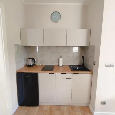 a kitchen with white cabinets and a black refrigerator at Apartament Sumik in Zator