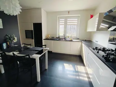 a kitchen with white cabinets and a table and a dining room at Apartament Sumik in Zator
