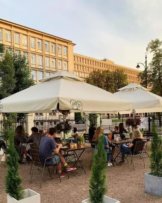 a group of people sitting at tables under an umbrella at Discover Krakow Apartments - 5 Borowickiej St - Studio next to Opera and Unity Centre in Kraków