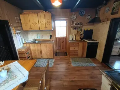 a kitchen with wooden cabinets and a wooden floor at Ludwikówka pod Luboniem, stu-letni domek w górach in Naprawa