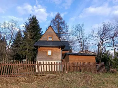 a wooden house with a fence in front of it at Ludwikówka pod Luboniem, stu-letni domek w górach in Naprawa
