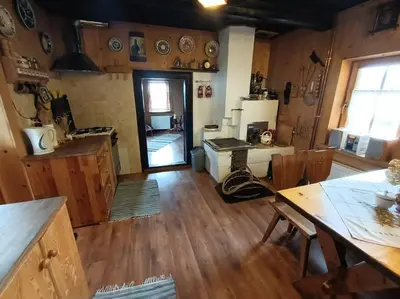 a kitchen with wooden floors and a kitchen with a stove at Ludwikówka pod Luboniem, stu-letni domek w górach in Naprawa