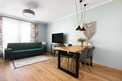 a living room with a table and a green couch at Mary&Arte Apartments Grzegórzecka 15 in Kraków