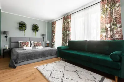 a living room with a green couch and a bed at Mary&Arte Apartments Grzegórzecka 15 in Kraków