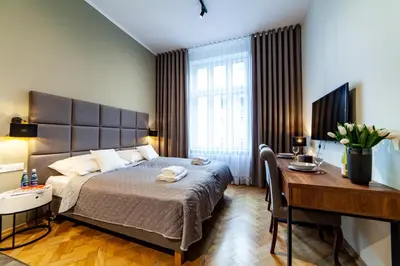 a bedroom with a bed and a table and a desk at MILU Apartments Kurkowa in Kraków