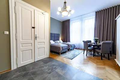 a bedroom with a bed and a table and a dining room at MILU Apartments Kurkowa in Kraków