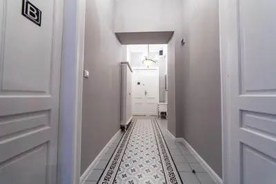 a hallway with white walls and a black and white tile floor at MILU Apartments Kurkowa in Kraków
