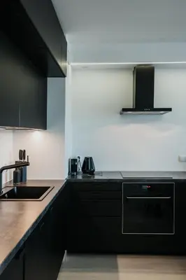 a kitchen with black cabinets and a sink at Arcade Old Town with Free Parking in Kraków
