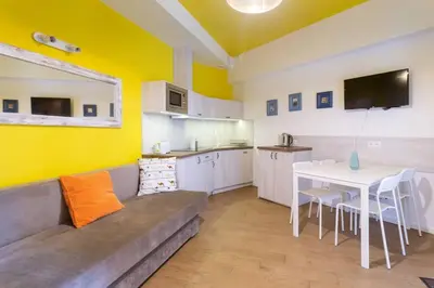 a living room with a couch and a table and a kitchen at Apartament w sercu krakowskiego Kazimierza in Kraków