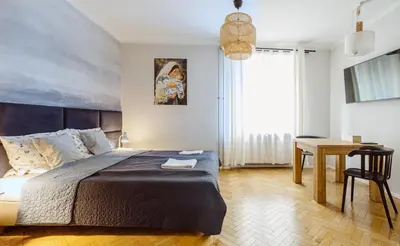 a bedroom with a bed and a table and a desk at Kana - Stylish Apartment in Kraków Pomorska - Close, WiFi, Smart TV in Kraków