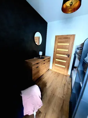 a bedroom with a wooden dresser and a mirror at Apartament Komfort 17 in Zator