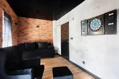 a living room with a black couch and a dart board at Victoria Apartment in Kraków